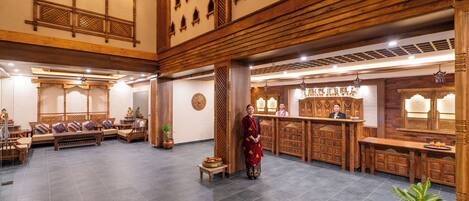 A spacious lobby with a reception desk, seating area, and decorative elements like wooden beams and traditional wall designs.