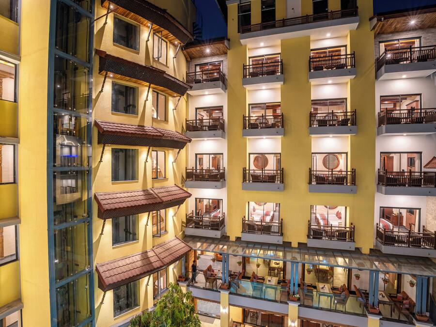 A multi-story hotel with balconies, outdoor seating, and a pool area.