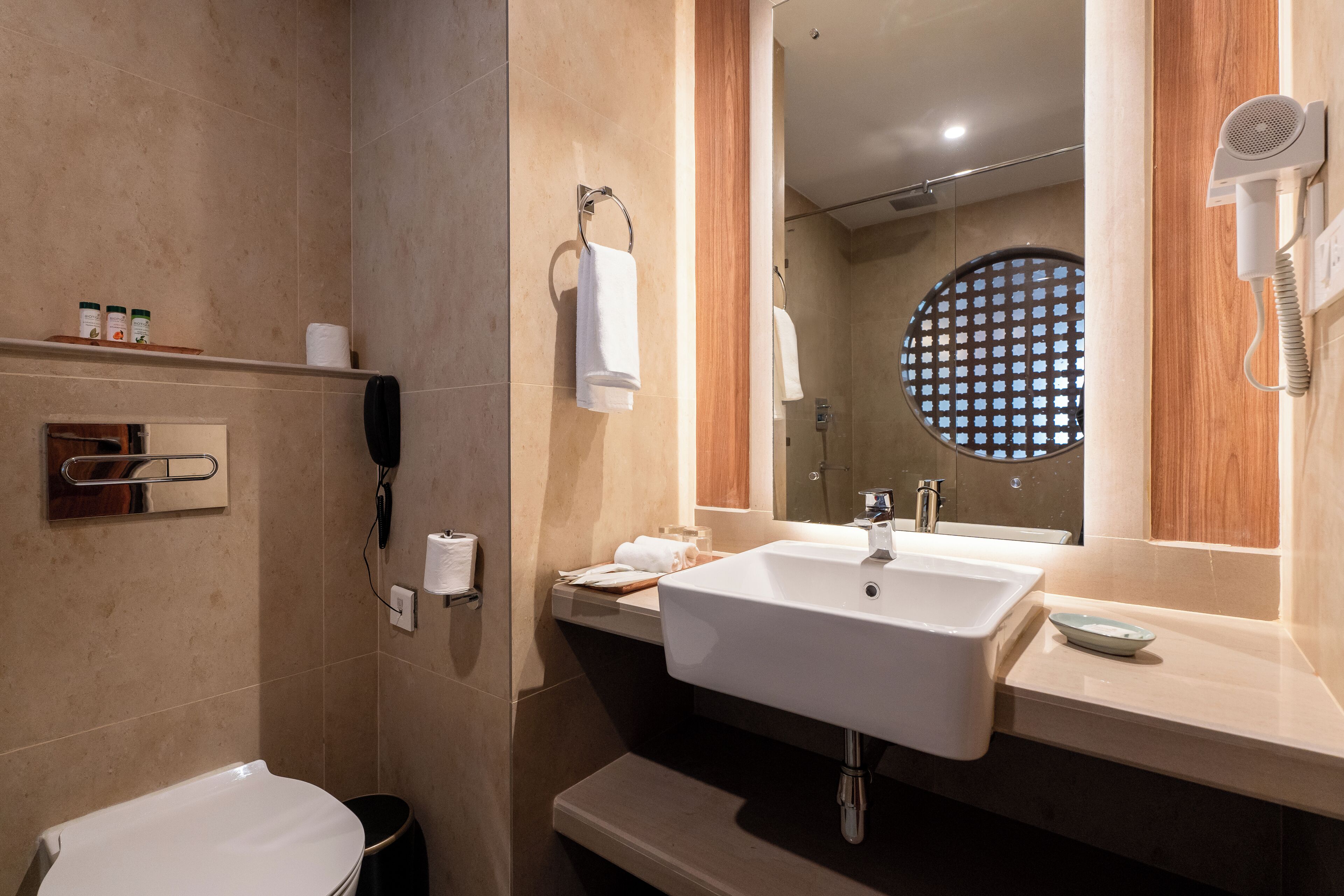 Een moderne badkamer met een wastafel, spiegel en een haardroger bevestigd aan de muur.