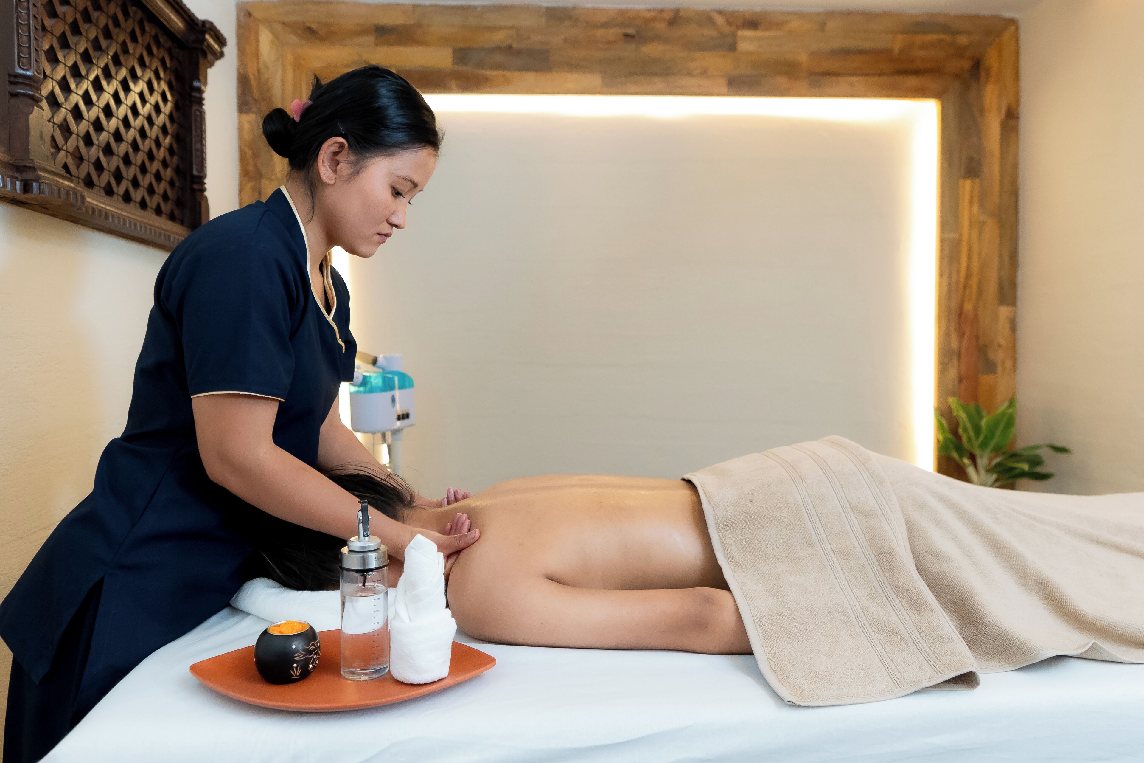 A massage therapy session in a spa setting with a wooden wall and a massage table.