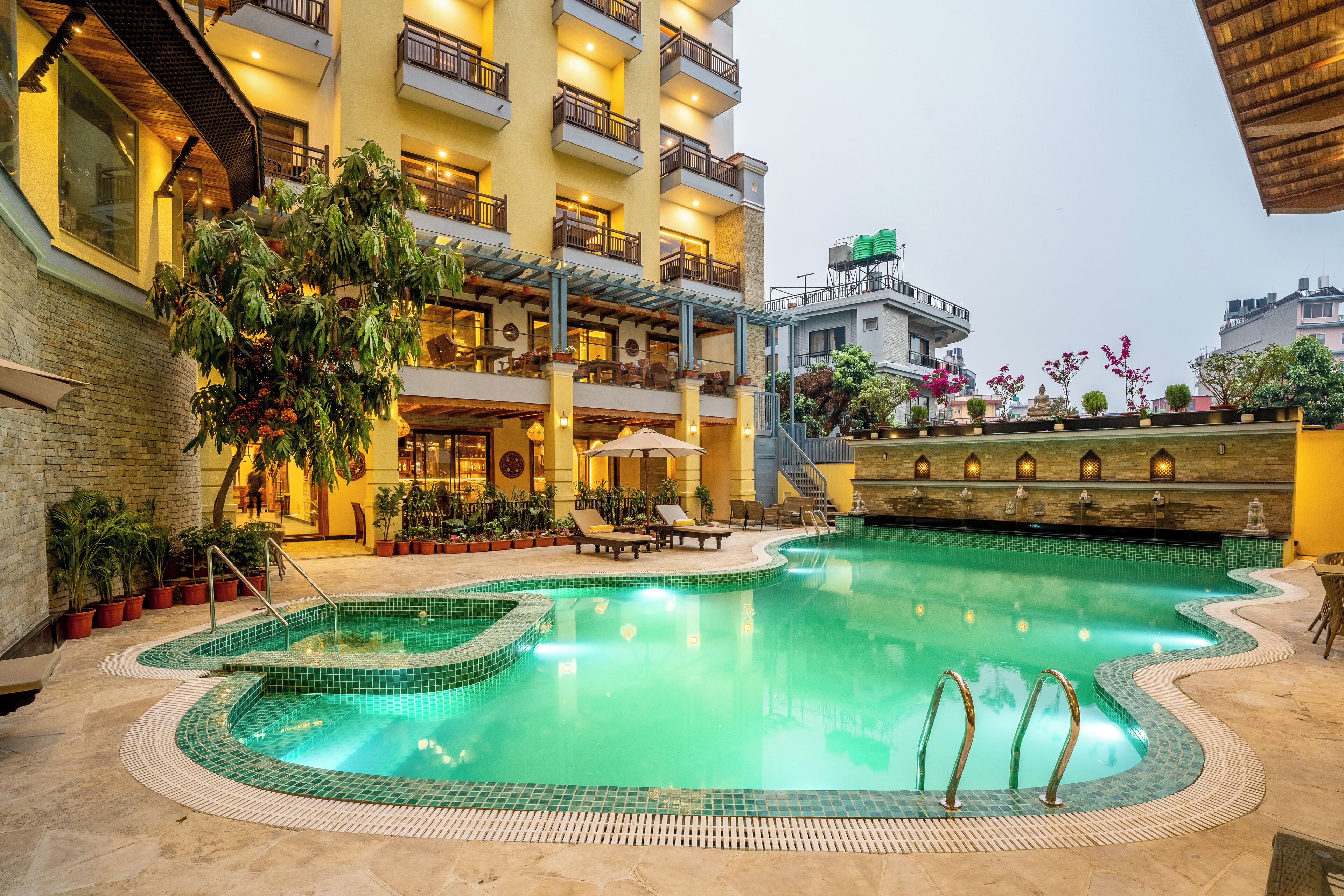 A hotel with a swimming pool, outdoor seating, and multiple balconies.