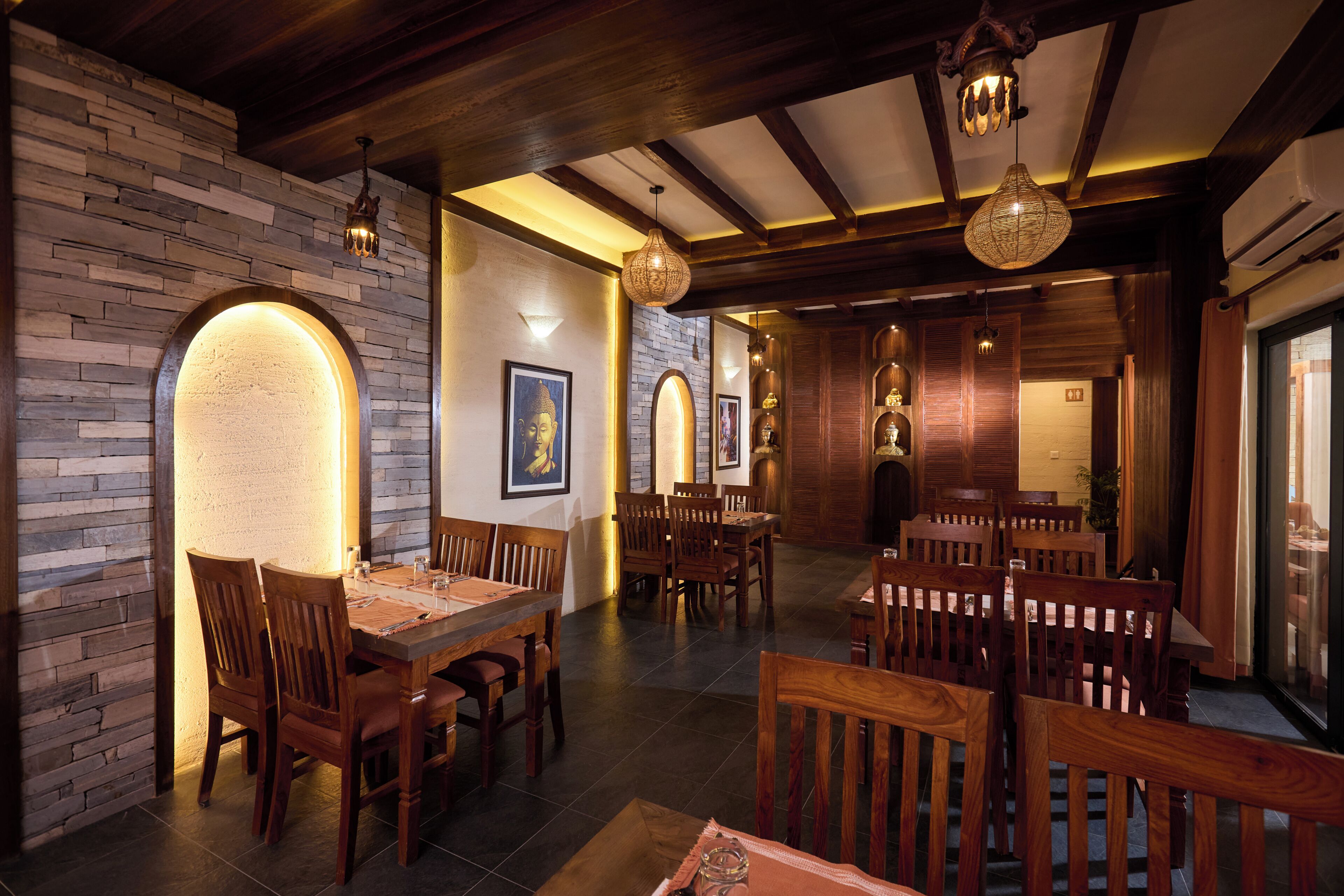 A restaurant with wooden furniture, stone walls, and hanging lights.