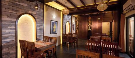 A restaurant with wooden furniture, stone walls, and hanging lights.