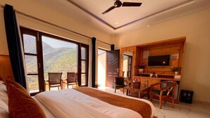A hotel room with two beds, a TV, a desk, and a balcony with chairs. - The kempty fall resort (Dhanaulti)