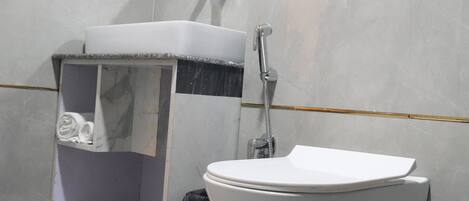 A modern bathroom with a white sink, a toilet, and a shower.
