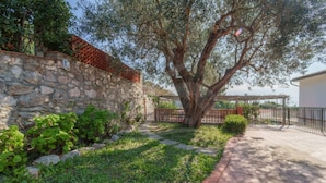 A stone wall, a large tree, and a paved pathway.