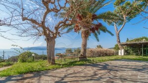 A stone pathway leading to a scenic overlook with a view of the sea and mountains.