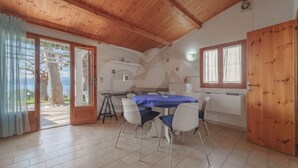 A dining area with a wooden ceiling, a table with chairs, and a view of the outdoors.