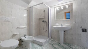 Ein Badezimmer mit Toilette, Bidet, Dusche und Waschbecken.