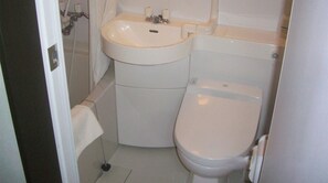 Ein kleines, kompaktes Badezimmer mit Toilette, Waschbecken und Dusche.