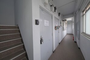rooms and offices line the corridor, with a staircase providing access to other areas.
