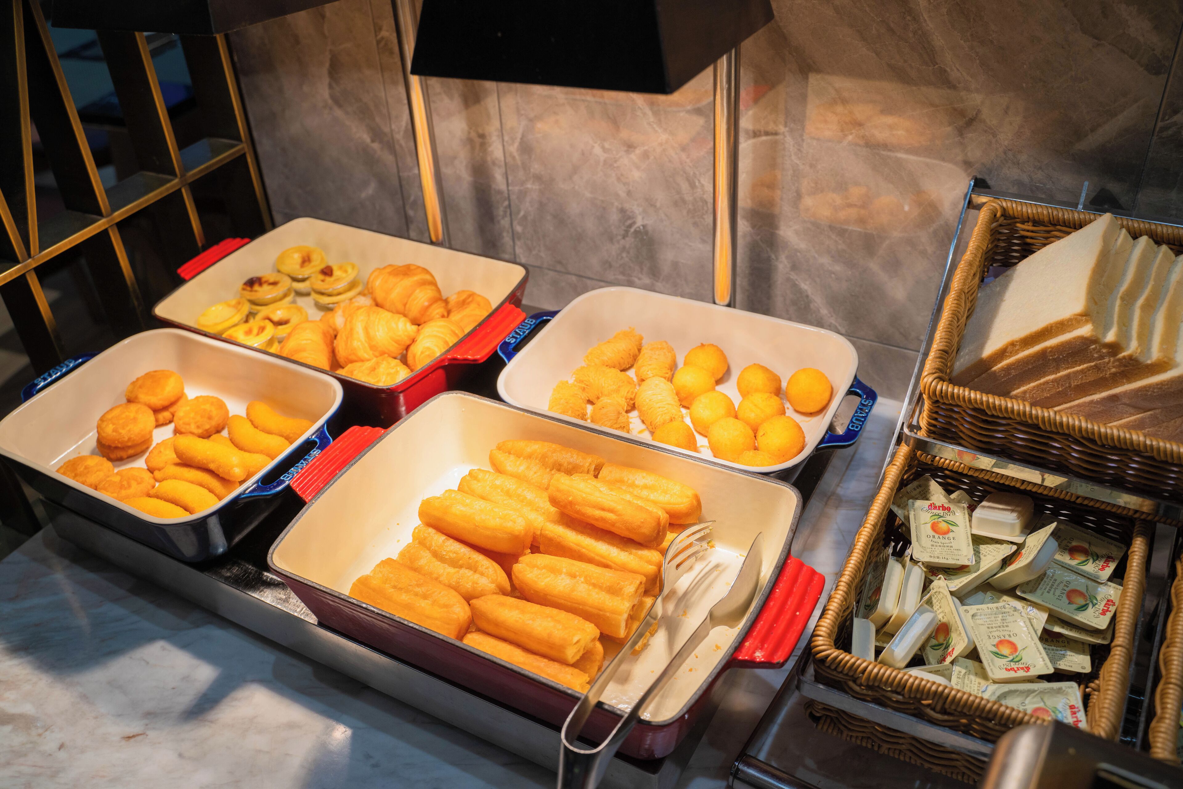A buffet with various food items including pastries, tater tots, and cheese.