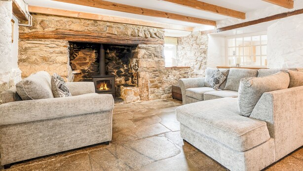 A cozy living room with a stone fireplace, wooden beams, and modern furniture.