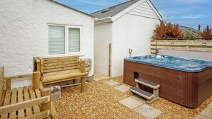 A hot tub, wooden bench, and a window with blinds.