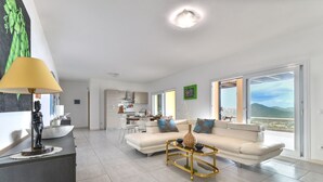 A spacious living area with a sofa, coffee table, and a view of the mountains through large windows.