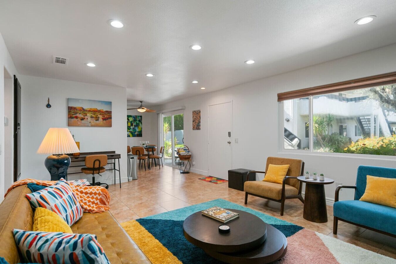 A modern living room with a sofa, armchairs, a coffee table, and a dining area with chairs and a table.
