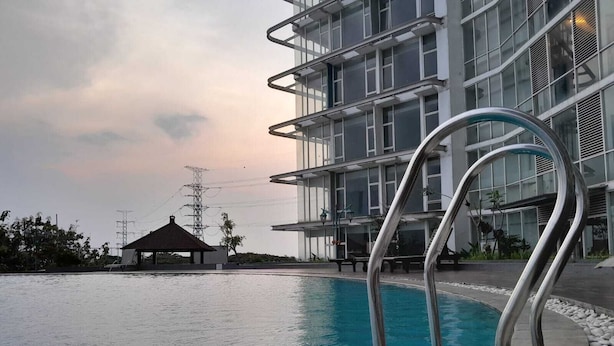 A swimming pool with metal railings, a gazebo, and a modern building with multiple floors and large windows. - Roket Room Majestic Point (Gading Serpong)