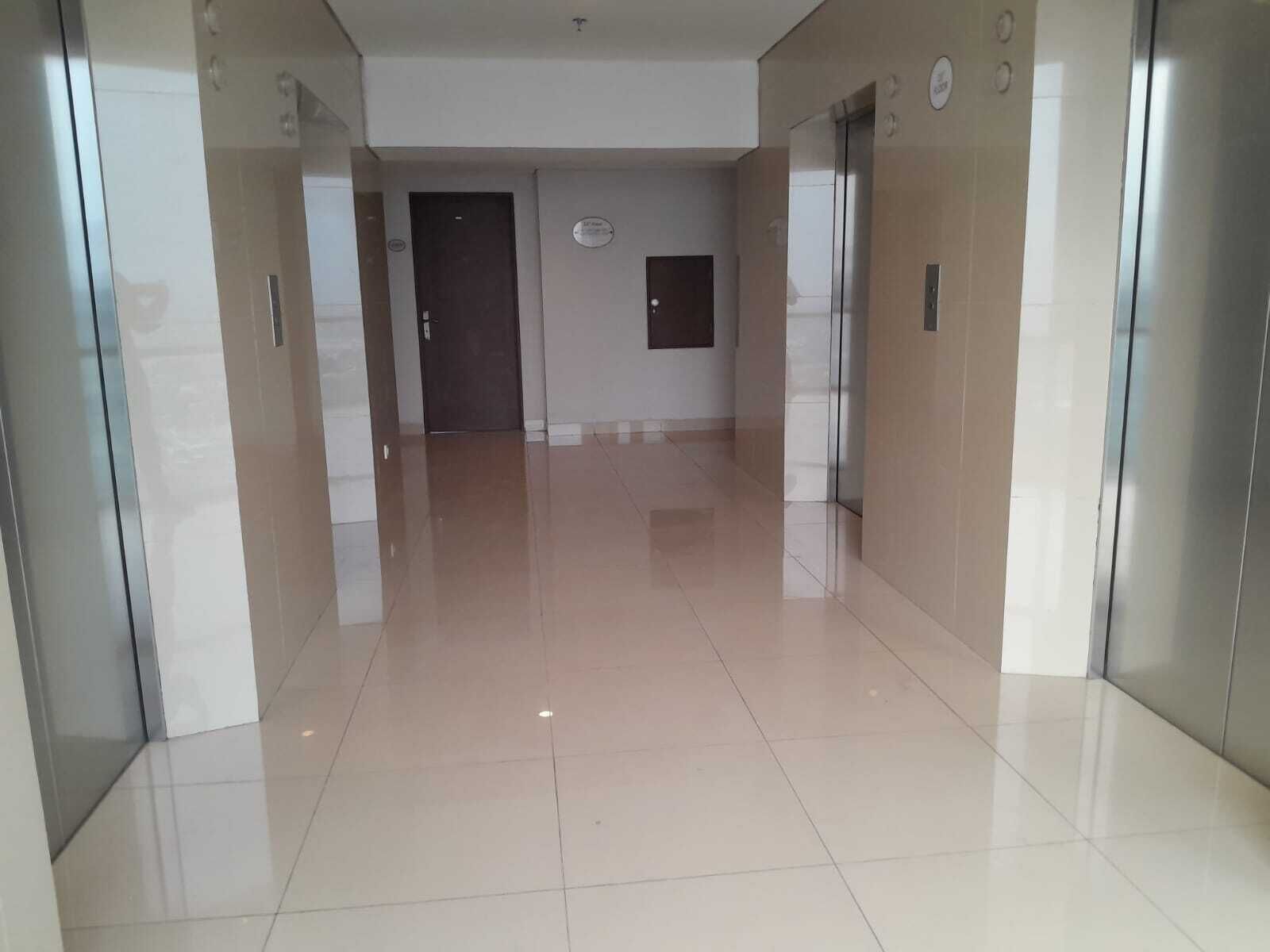 A clean, modern hallway with a shiny tiled floor, a door at the end, and a small sign on the wall.