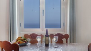 Una mesa de comedor con una botella de vino, dos copas y un bol de fruta.