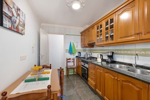 Une cuisine avec des meubles de rangement en bois, un plan de travail, un évier et une table à manger avec des chaises.