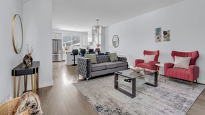 A modern living room with a grey sofa, red armchairs, and a glass coffee table. - Stylish 4-Bedroom & Fireplace (Mainfloor Bedroom & Full Bathroom) (Calgary)