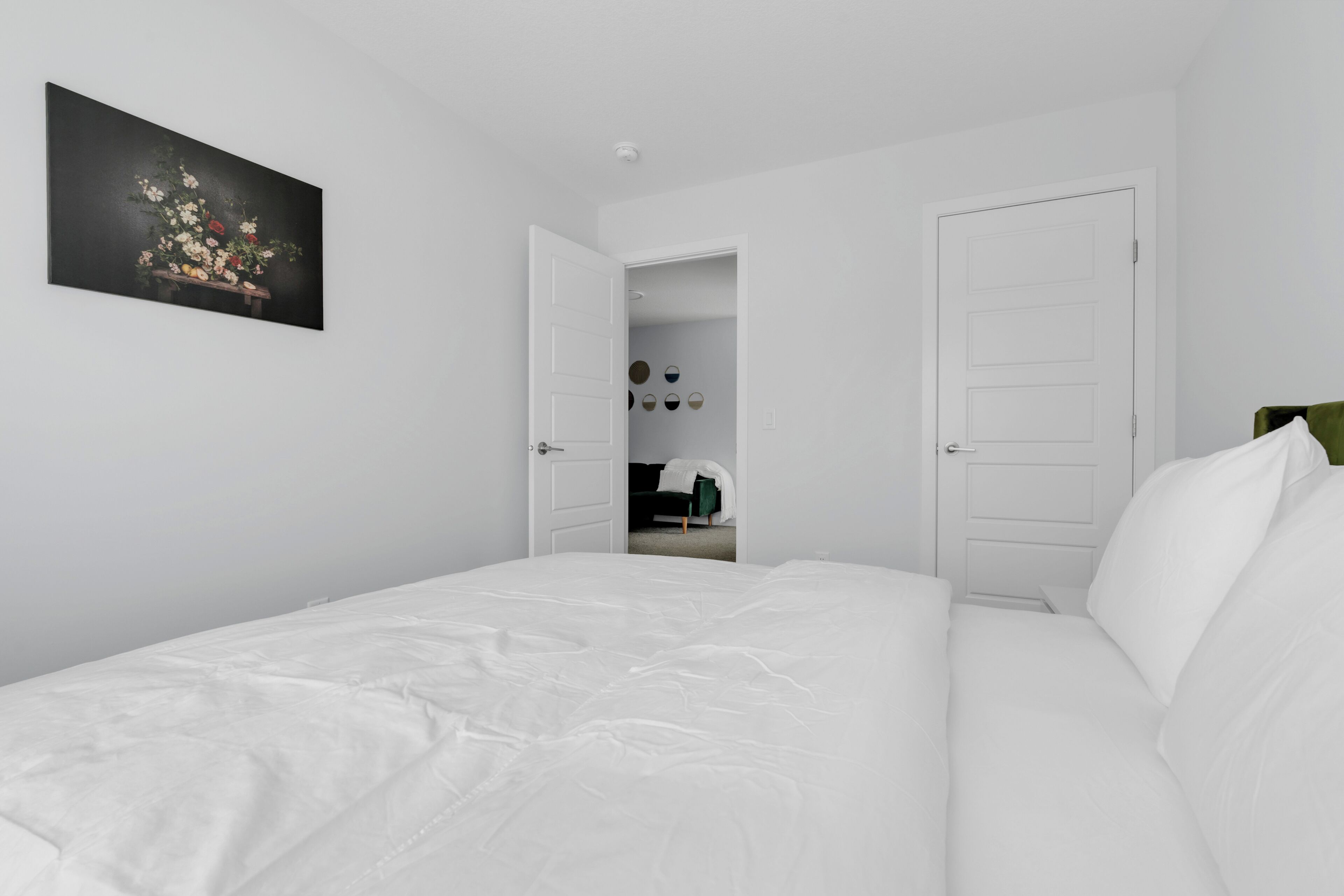 A bedroom with a large bed, white walls, and a door leading to a bathroom.