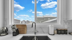 A kitchen with a large window, a sink, and various kitchen items. - Stylish 4-Bedroom & Fireplace (Mainfloor Bedroom & Full Bathroom) (Calgary)