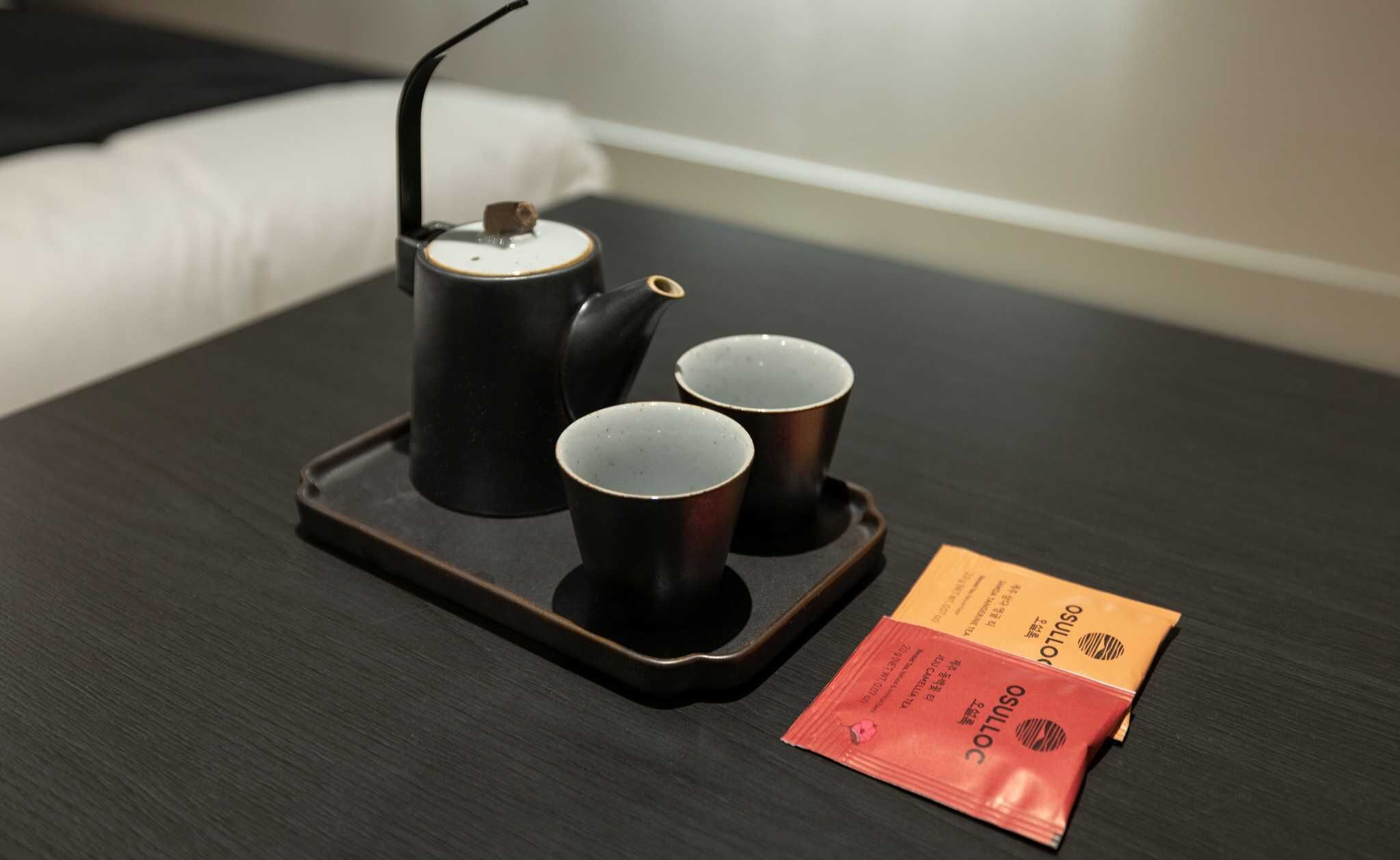 A tray with a teapot and two cups on a dark wooden table.