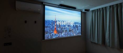 A projection screen in a room with a cityscape view, air conditioning unit, and curtains.