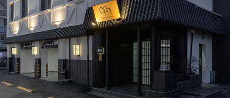 A building with a modern facade, a sign reading "AANK RYOKAN," and a traditional tiled roof.