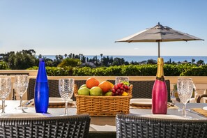 A table set with a fruit basket, a champagne bottle, and empty wine glasses, overlooking a scenic view. - Casa Jean - Private villa with sea view and heatable pool (Carvoeiro)
