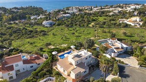 A coastal residential area with houses, a swimming pool, and a view of the sea. - Casa Jean - Private villa with sea view and heatable pool (Carvoeiro)