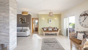 A spacious living area with a modern sofa, a classic armchair, and a large wall clock. - Villa Rosati - Luxury villa with private pool and Jacuzzi close to town center (Carvoeiro)
