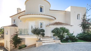 A modern two-story house with a curved facade, a small balcony, and a well-maintained garden. - Villa Rosati - Luxury villa with private pool and Jacuzzi close to town center (Carvoeiro)