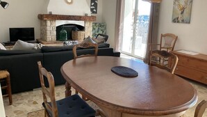 A cozy living room with a fireplace, a dining table, and a sofa. - Vacation rental 4 people arrière pays grassois (Cabris)