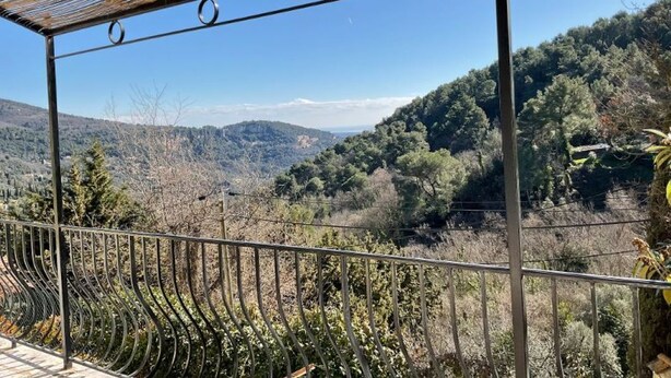 A covered outdoor area with a metal railing, offering a view of a hilly landscape with trees and a clear sky. - Vacation rental 4 people arrière pays grassois (Cabris)