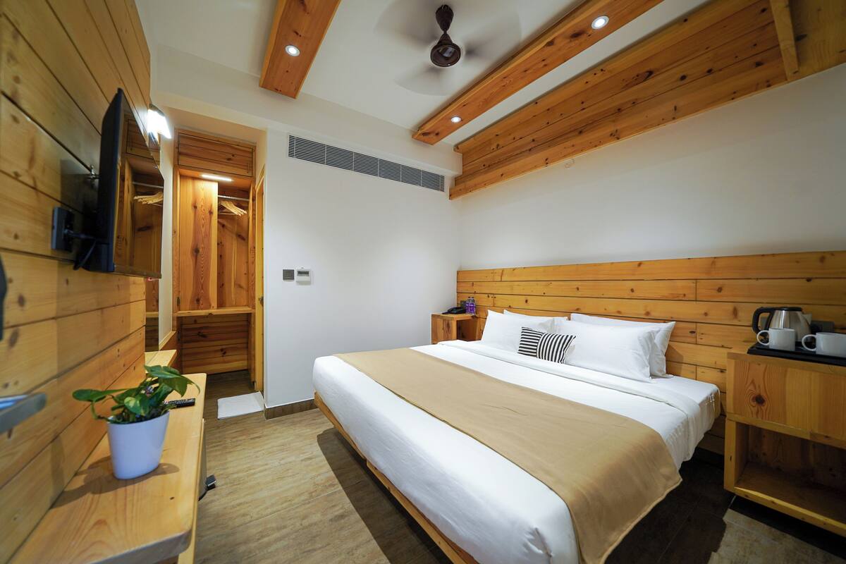A wooden-paneled bedroom with a bed, bedside tables, a TV, and a ceiling fan.