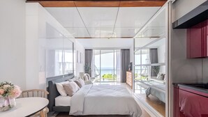 Een moderne slaapkamer met een groot bed, een eettafel en uitzicht op zee.