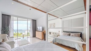 Een moderne hotelkamer met een ruim balkon, een bed, een slaapbank en een televisie.