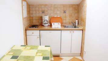 Una cocina compacta con cafetera, un lavabo y un mueble pequeño.