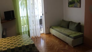 Una habitación pequeña y acogedora con una mesa a cuadros, un sofá con funda verde y un cuadro en la pared.
