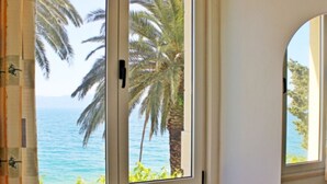 Una habitación con vista al océano y palmeras a través de una ventana.
