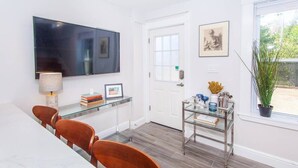 Un comedor moderno con televisor, una mesa de cristal y sillas.