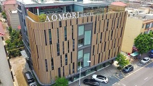 A modern hotel with a vertical wooden facade and a clear sign reading "AOMOR HOTEL". - Aomori Hotel (Foshan)