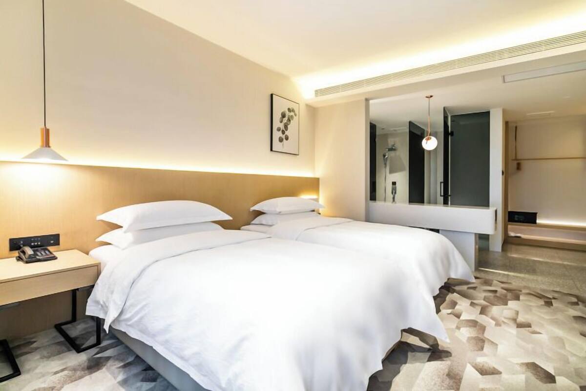 Quarto de hotel moderno com uma cama grande, mesas de cabeceira, uma escrivaninha e um espelho.