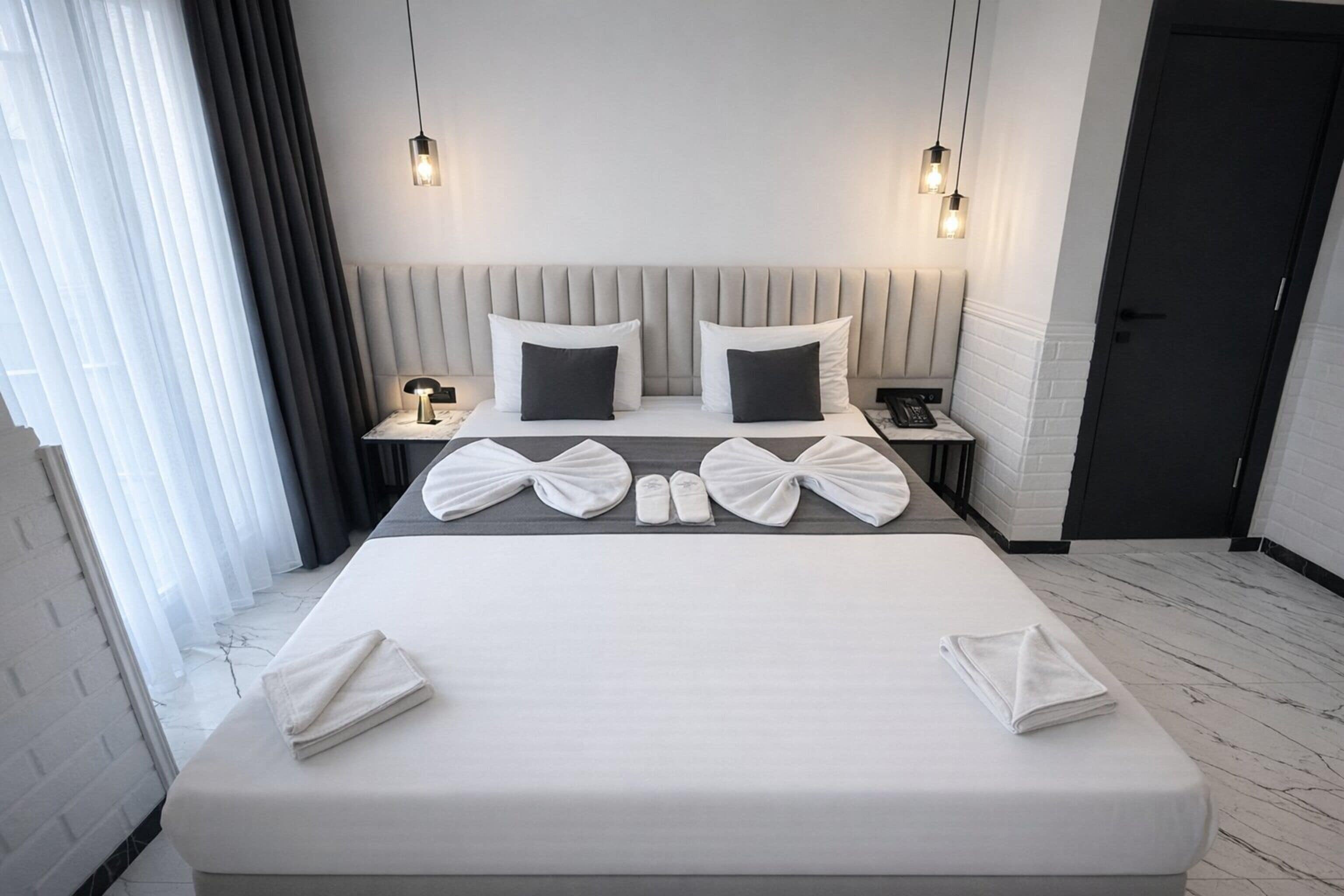 Et moderne hotelværelse med en stor seng, sengeborde og en neutral farvepalet.