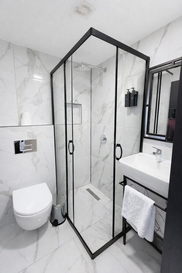 A modern bathroom with a glass-enclosed shower, a white toilet, and a sink with a towel rack. - D Twins plus Hotel (Arnavutköy)