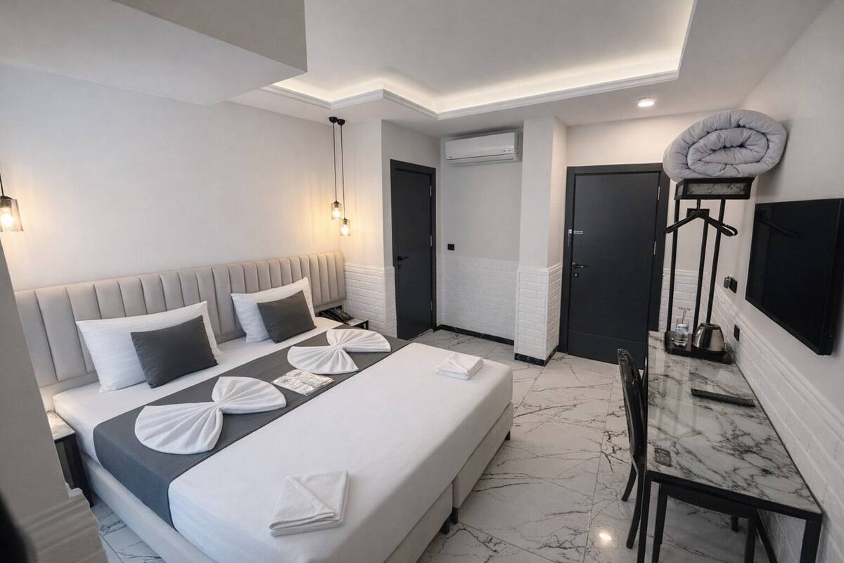 Una habitación de hotel moderna con una cama grande, una mesa de comedor y un televisor montado en la pared.