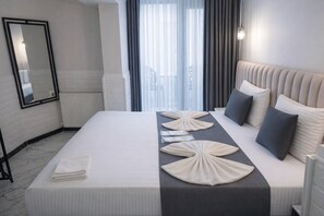 A modern hotel room with a neatly made bed, a large mirror, and a view of the outdoors through sheer curtains. - D Twins plus Hotel (Arnavutköy)