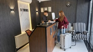 Un comptoir d’accueil avec une enseigne indiquant « DTWINS », situé dans un intérieur moderne aux murs rayés et au sol en marbre.